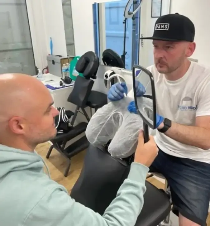 Stuart showing a client the result in a hand mirror
